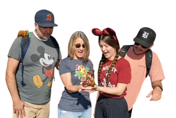 Four people standing together outdoors, smiling and looking at a small stuffed toy held by a young woman in a red Mickey Mouse shirt with a red bow in her hair.