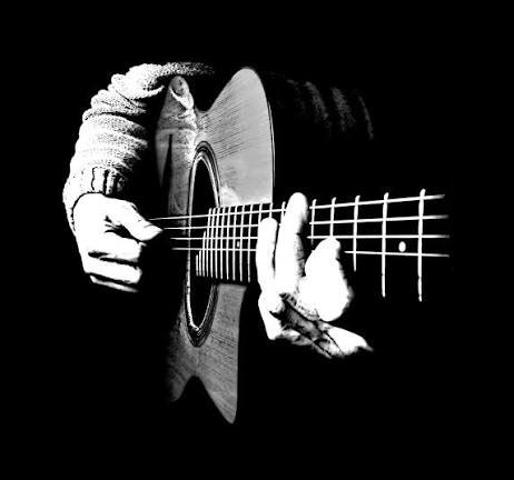 Une personne jouant de la guitare acoustique en noir et blanc.