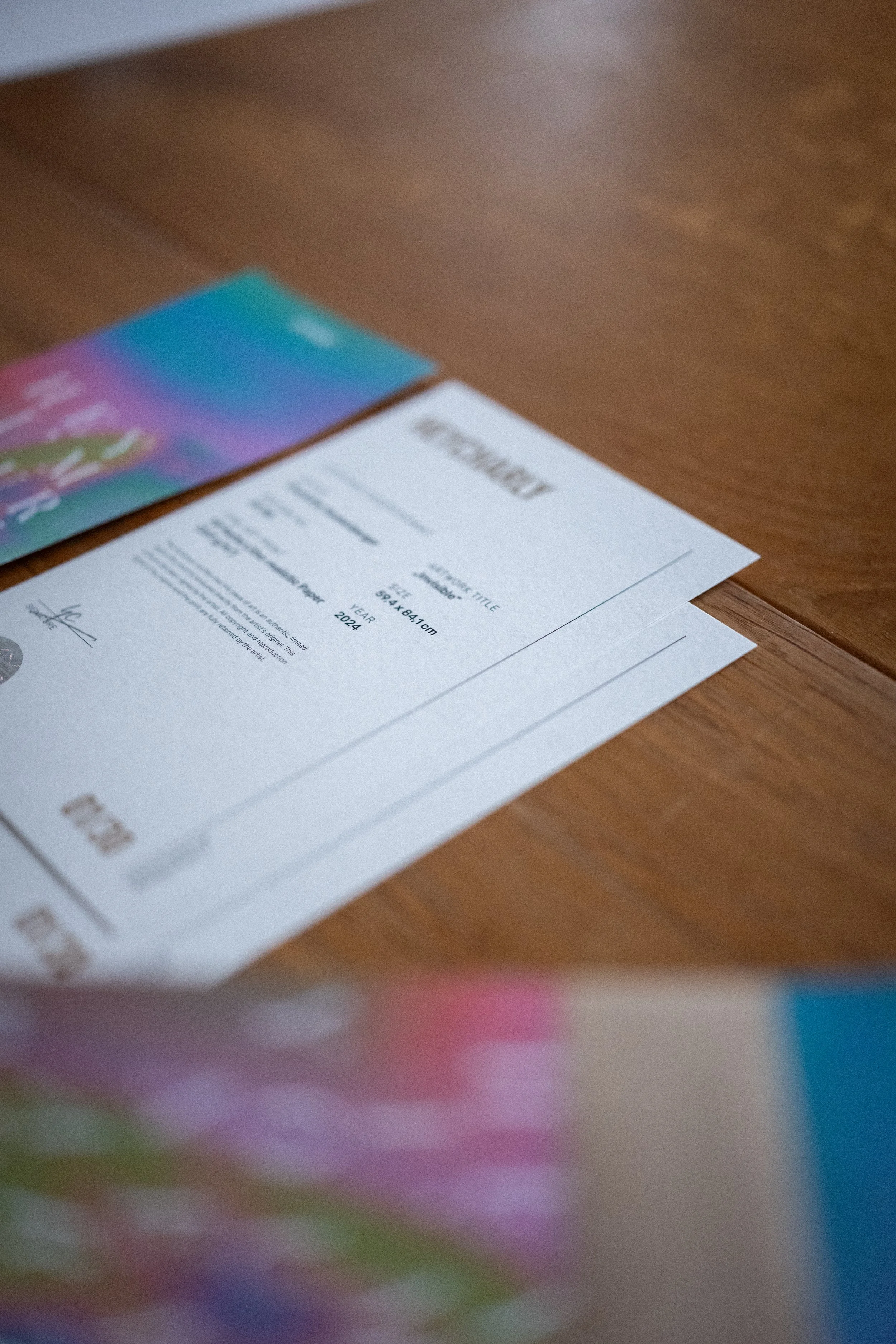 Die Aufnahme zeigt eine Oberfläche mit mehreren Druckmaterialien und einem bunten Flyer, die auf einem Holztisch liegen.