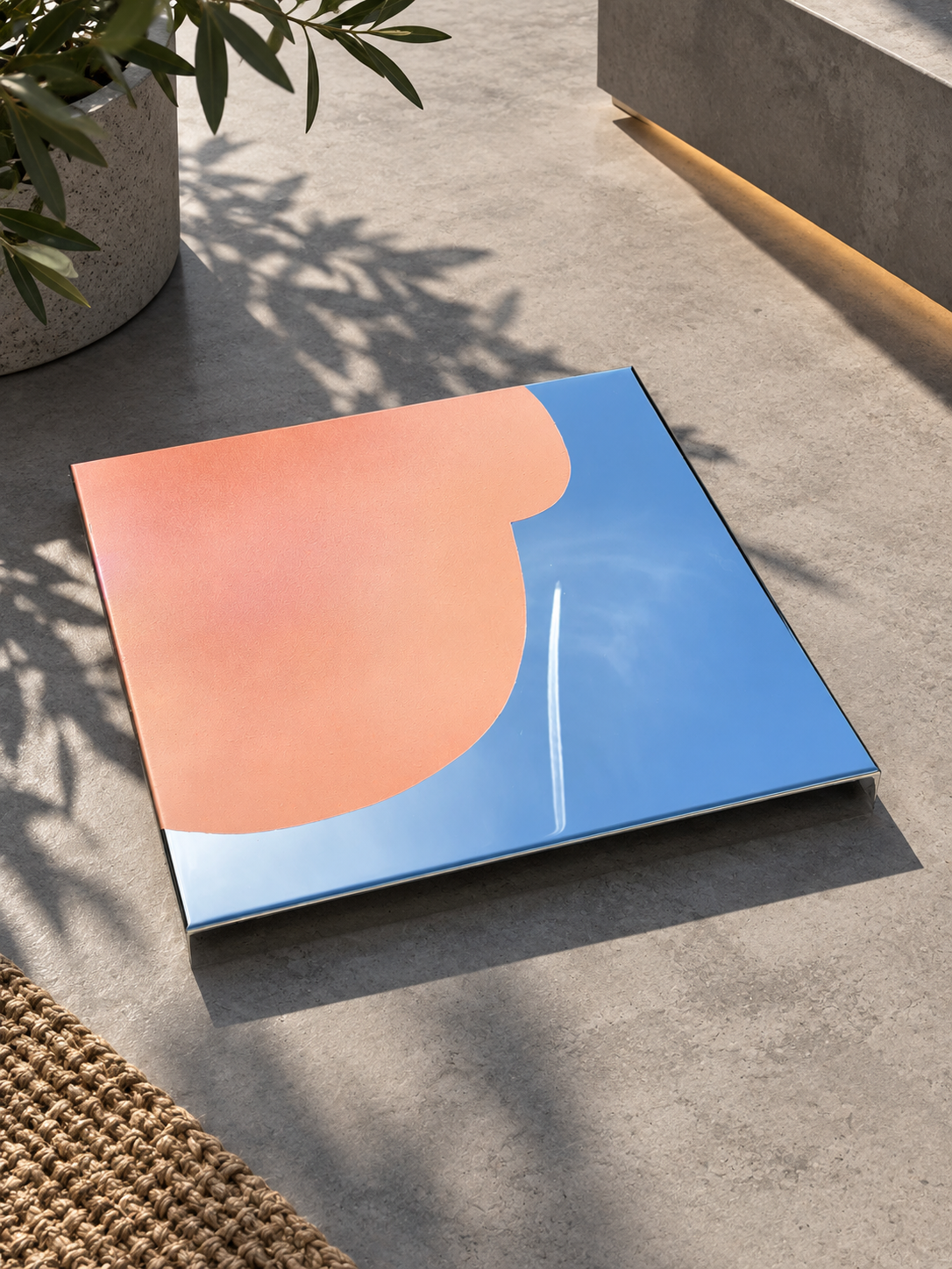 Modernes Spiegel-Artwork mit reflektierendem Himmel und Wolken, auf glattem Boden, neben einer Pflanze