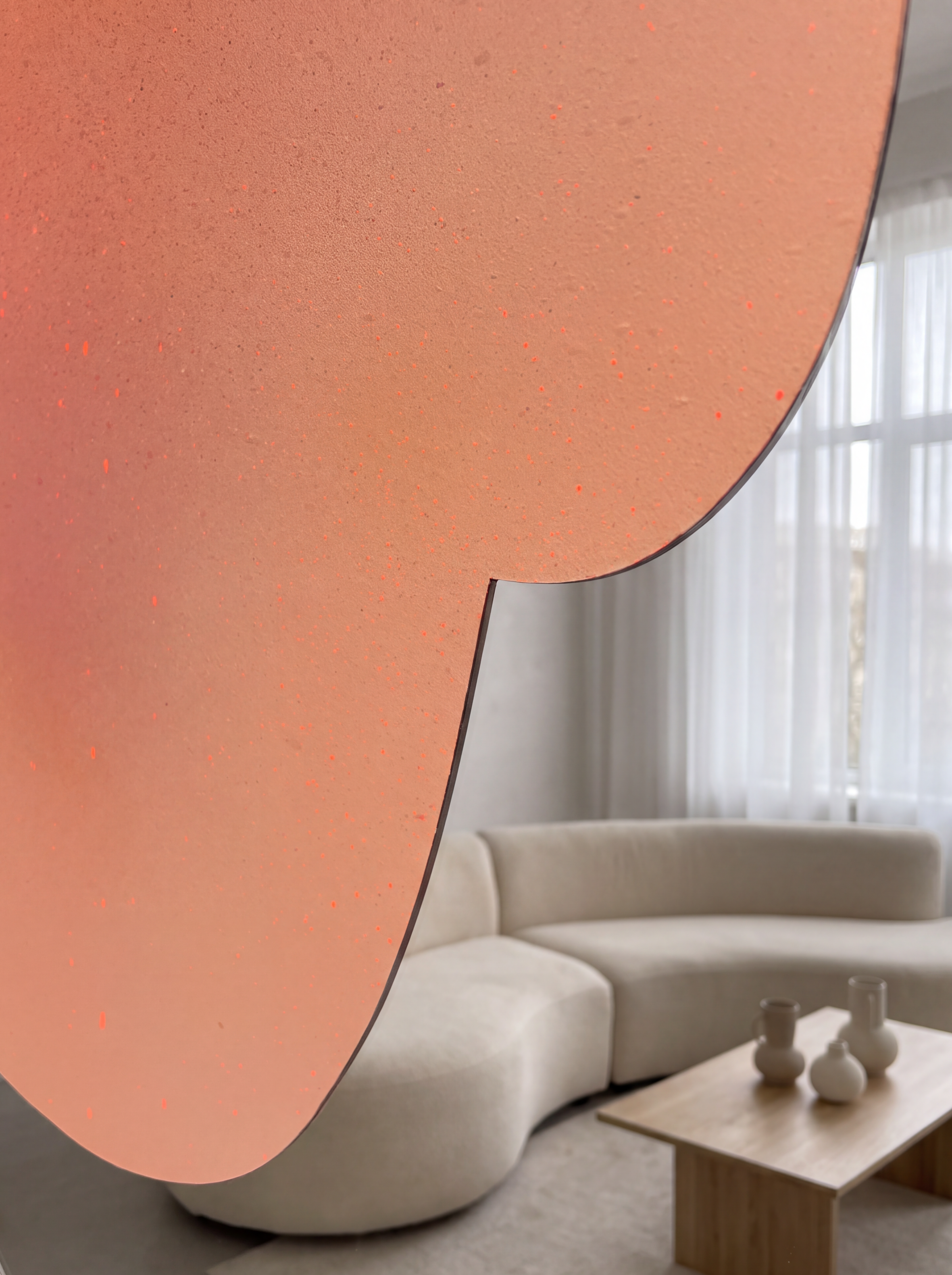 Ein modernes Artwork auf spiegelpoliertem Edelstahl, mit leuchtenden Pastellfarben, zeigt einen Loft-Raum mit beigem, geschwungenem Sofa, großen Fenstern mit Vorhängen und einem Designer Couchtisch.