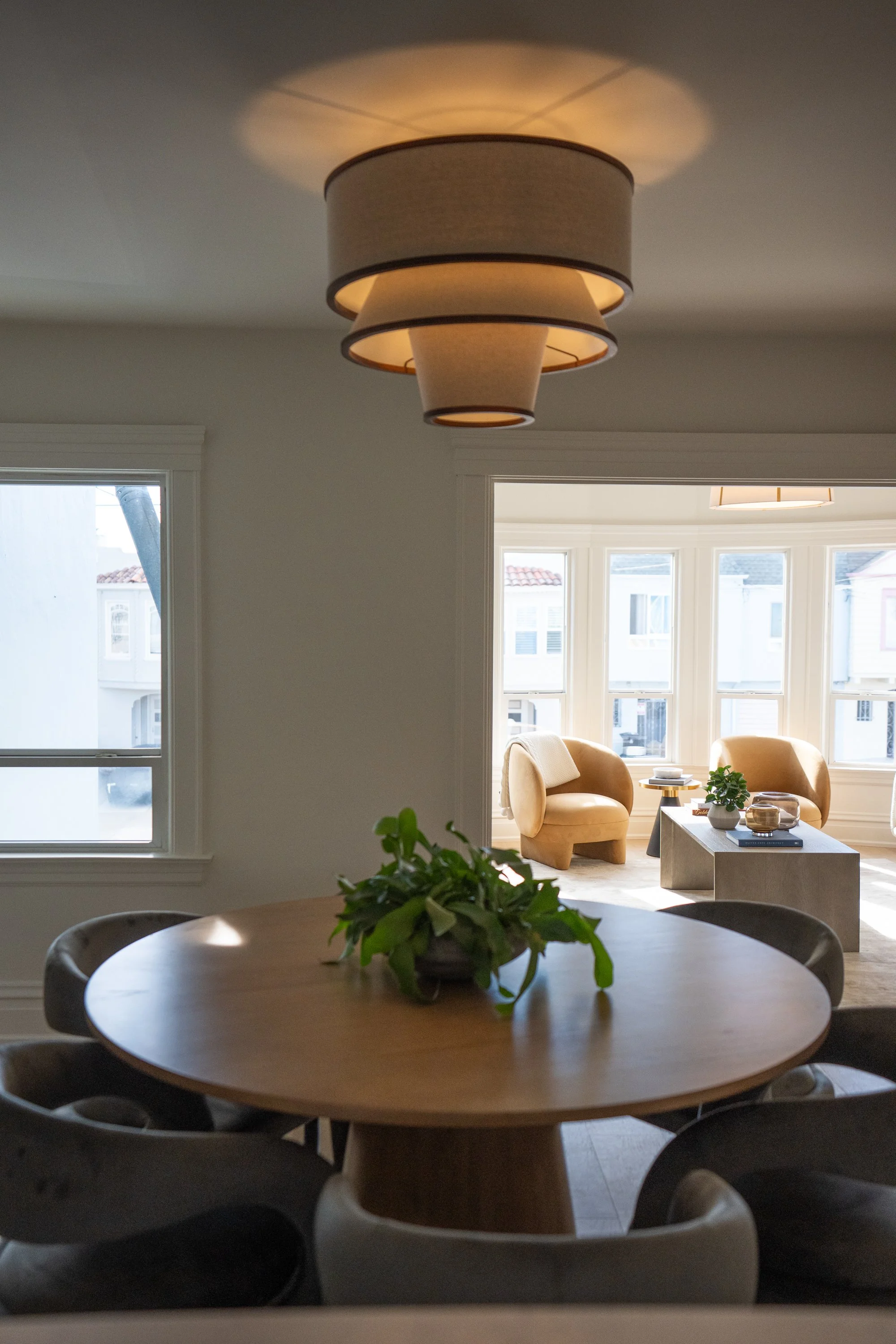 Living room with beige armchairs, coffee table, large window, and pendant ceiling light.