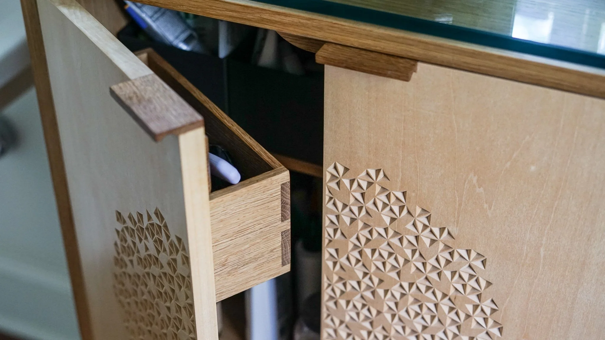 Close-up of wooden vanity cabinet with handmade geometric carvings with a door ajar.