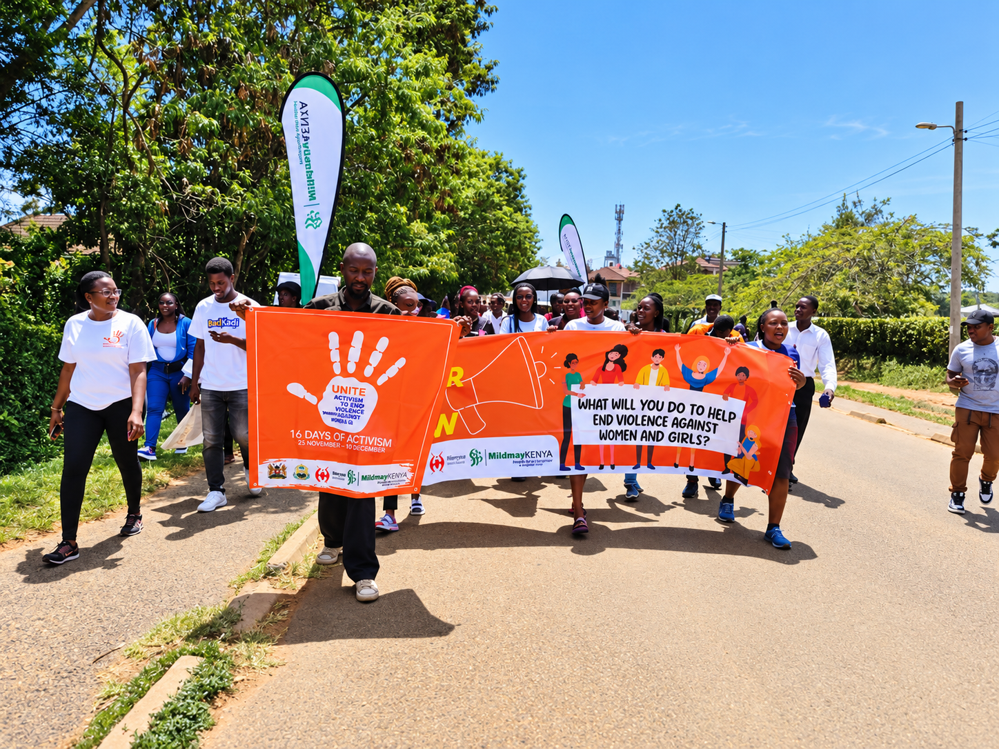 A group of people participating in a march or rally outdoors, holding banners that promote ending violence against women and girls during a campaign in Kenya.