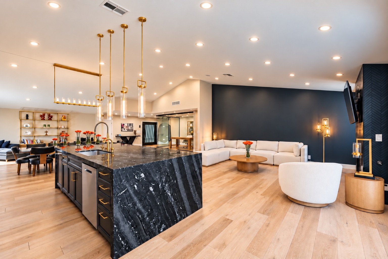 Modern open-concept living room with a kitchen island, white sectional sofa, dark accent wall, light wood flooring, and gold accents.