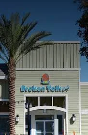 Front view of a building with a palm tree, green siding, and a sign that reads 'Brooke Yeller' in decorative blue letters.