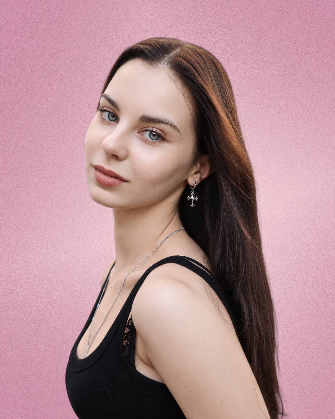 A young woman with long, dark hair against a pink background, wearing a black tank top and silver jewelry.