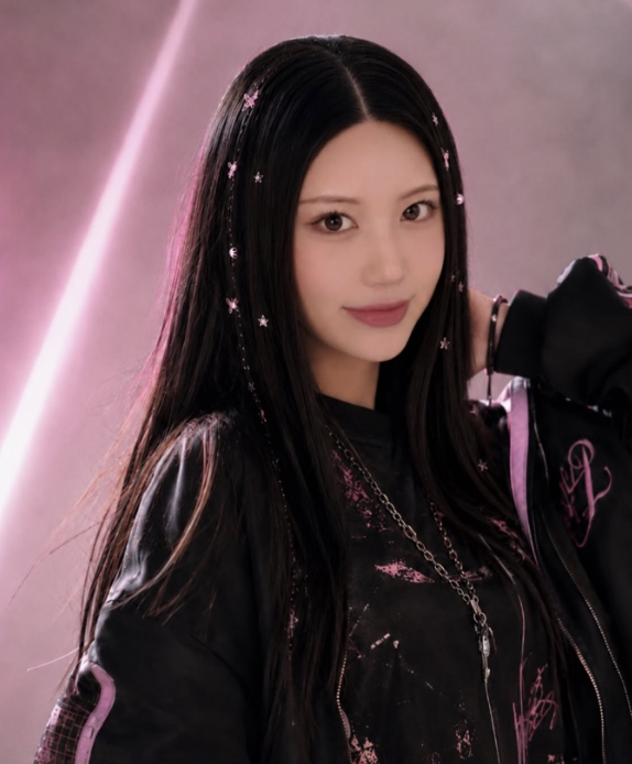 Young woman with long black hair adorned with small pink star-shaped accessories, wearing a black jacket with pink accents, standing in front of a pink neon-lit wall. Rosalie Han, Kpop Dance Dublin