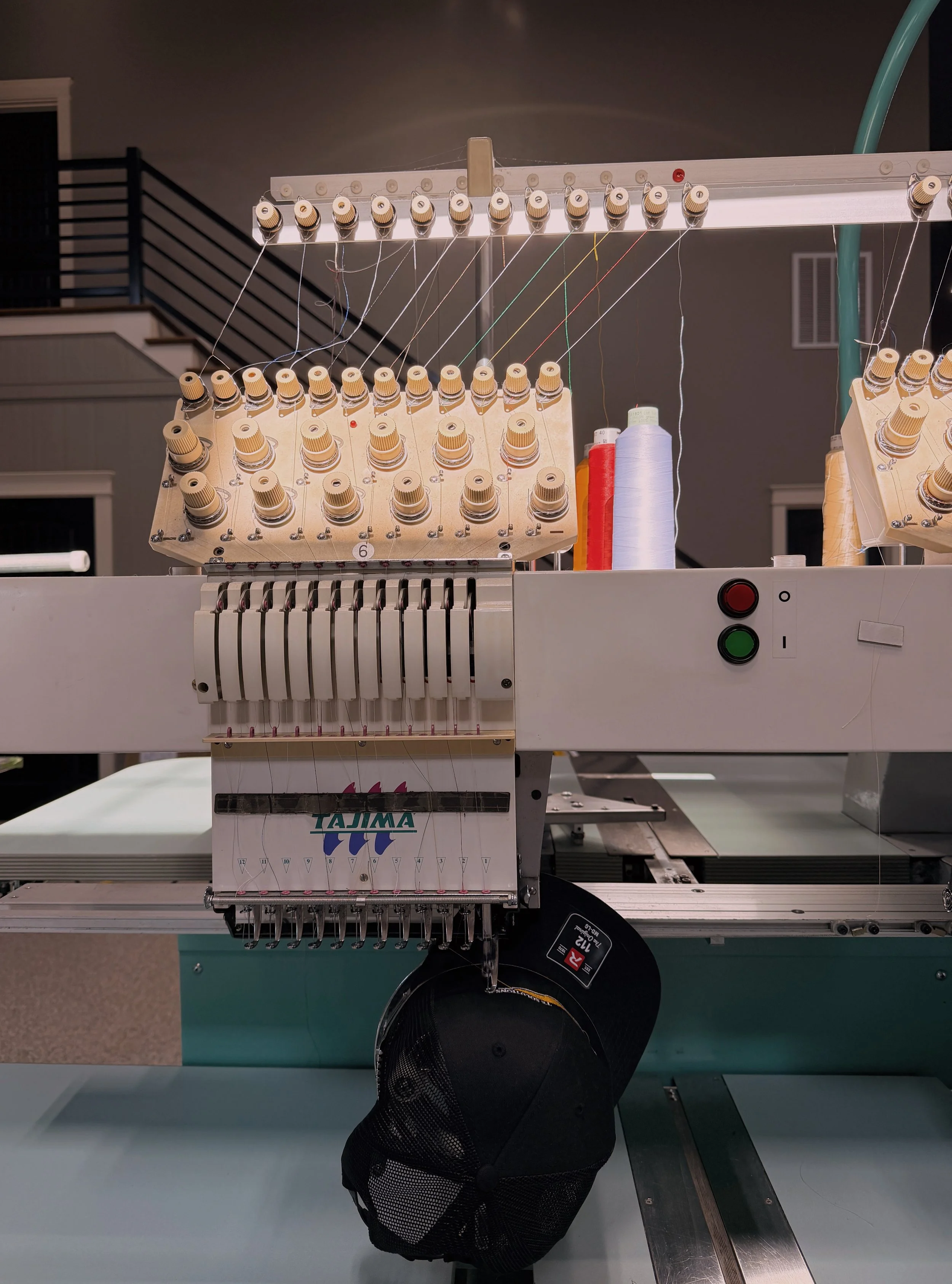 A sewing machine with multiple threads and spools, set in an indoor environment.