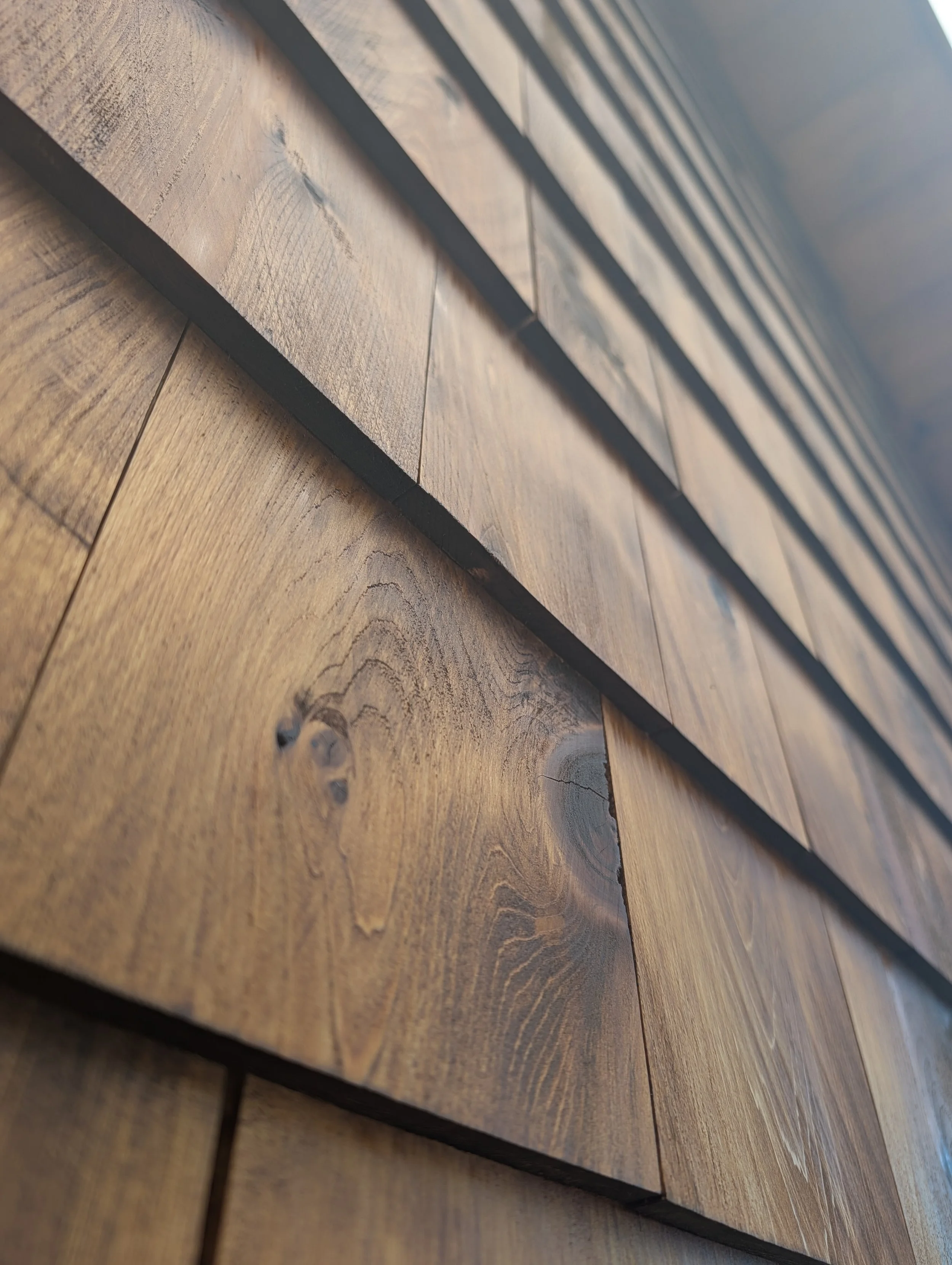 Close-up of a wooden surface with a series of horizontal dark-colored metal strips or strips of wood layered on top.