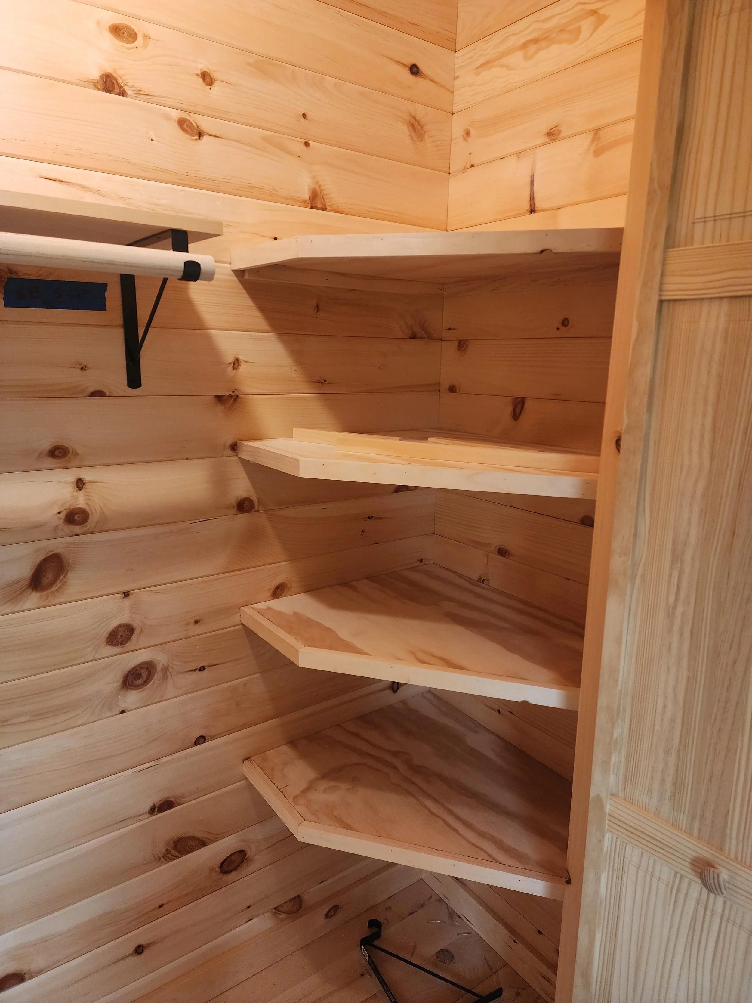 Wooden shelves inside a corner of a room with wood-paneled walls.