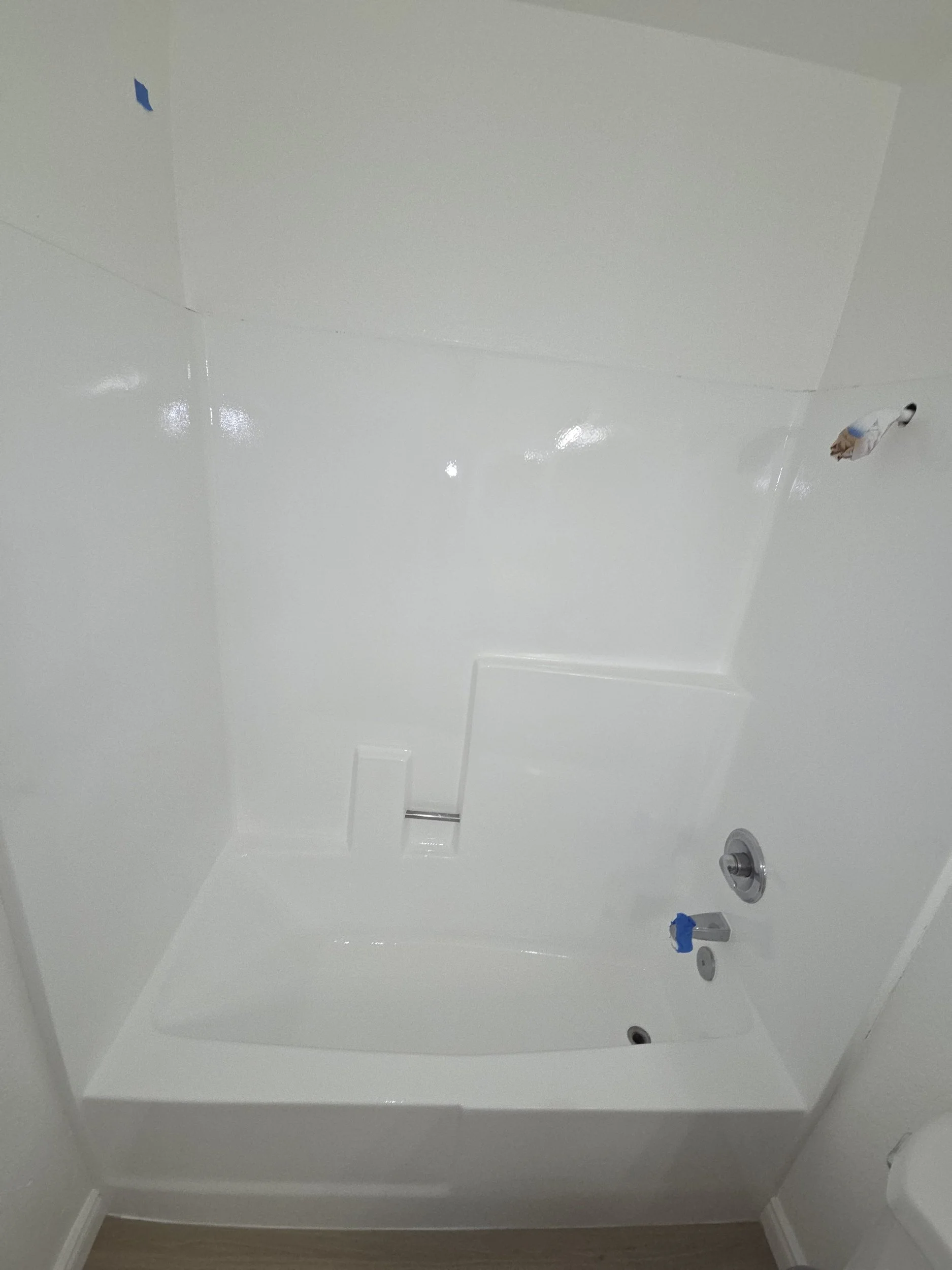 Empty white bathtub in a bathroom with fixtures and a drain.