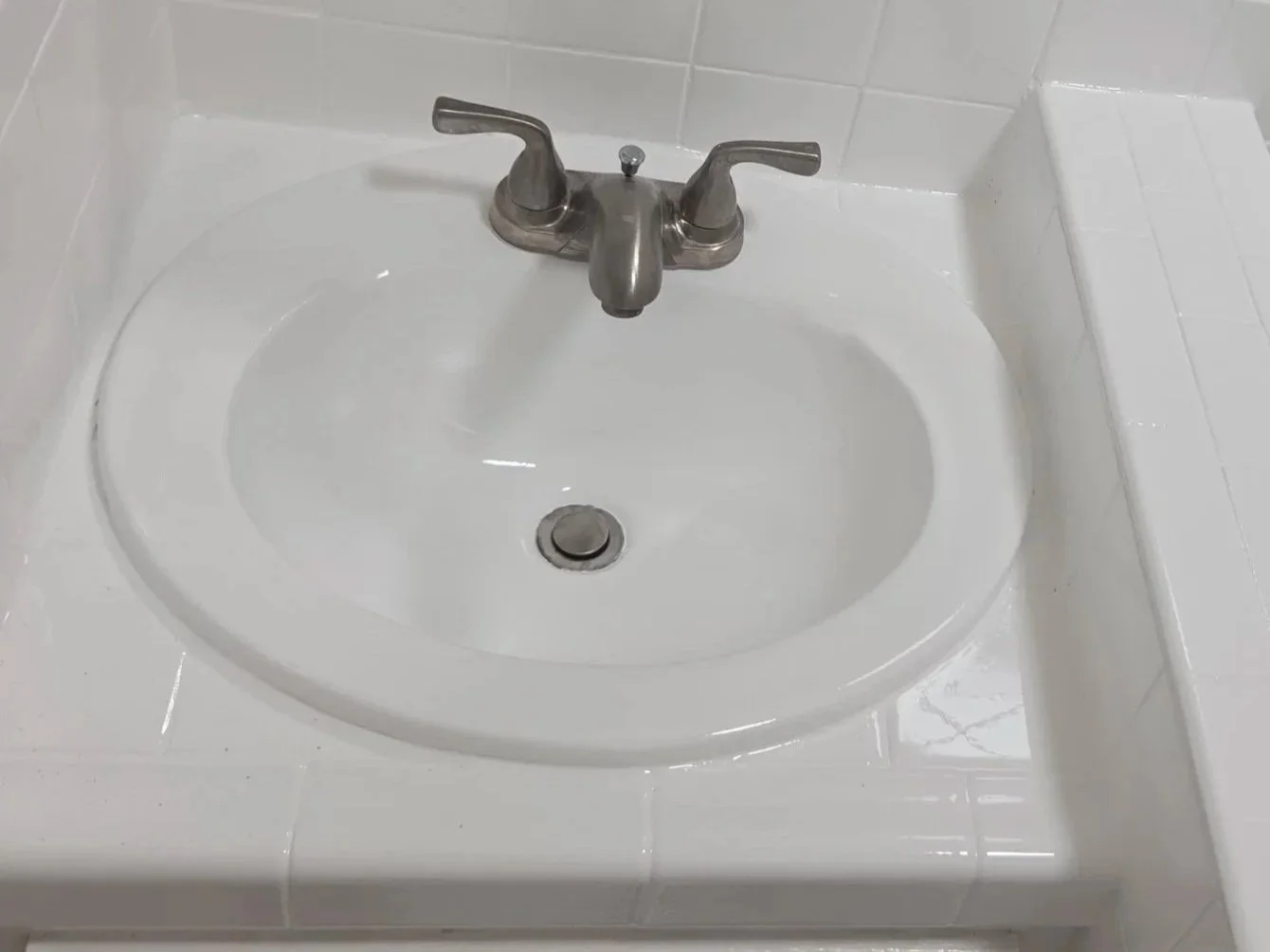 White bathroom sink with a silver faucet and a round drain.