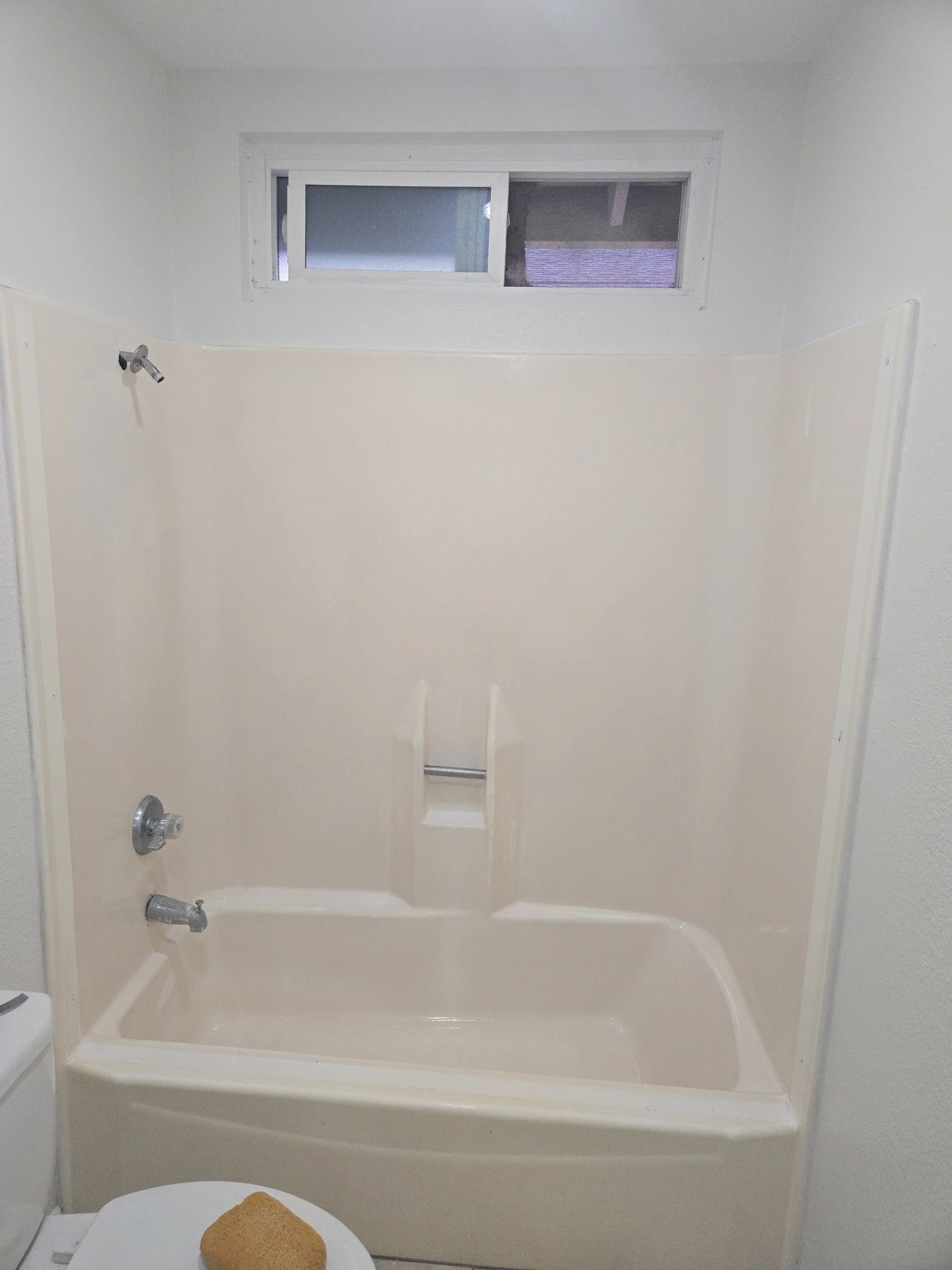 Private bathroom with a shower, a small frosted window, and a toilet with a brown towel on it.