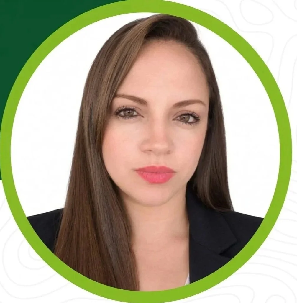 Retrato de una mujer con cabello largo y rubio, vestida con un saco negro, fondo blanco y un marco verde alrededor de la imagen.