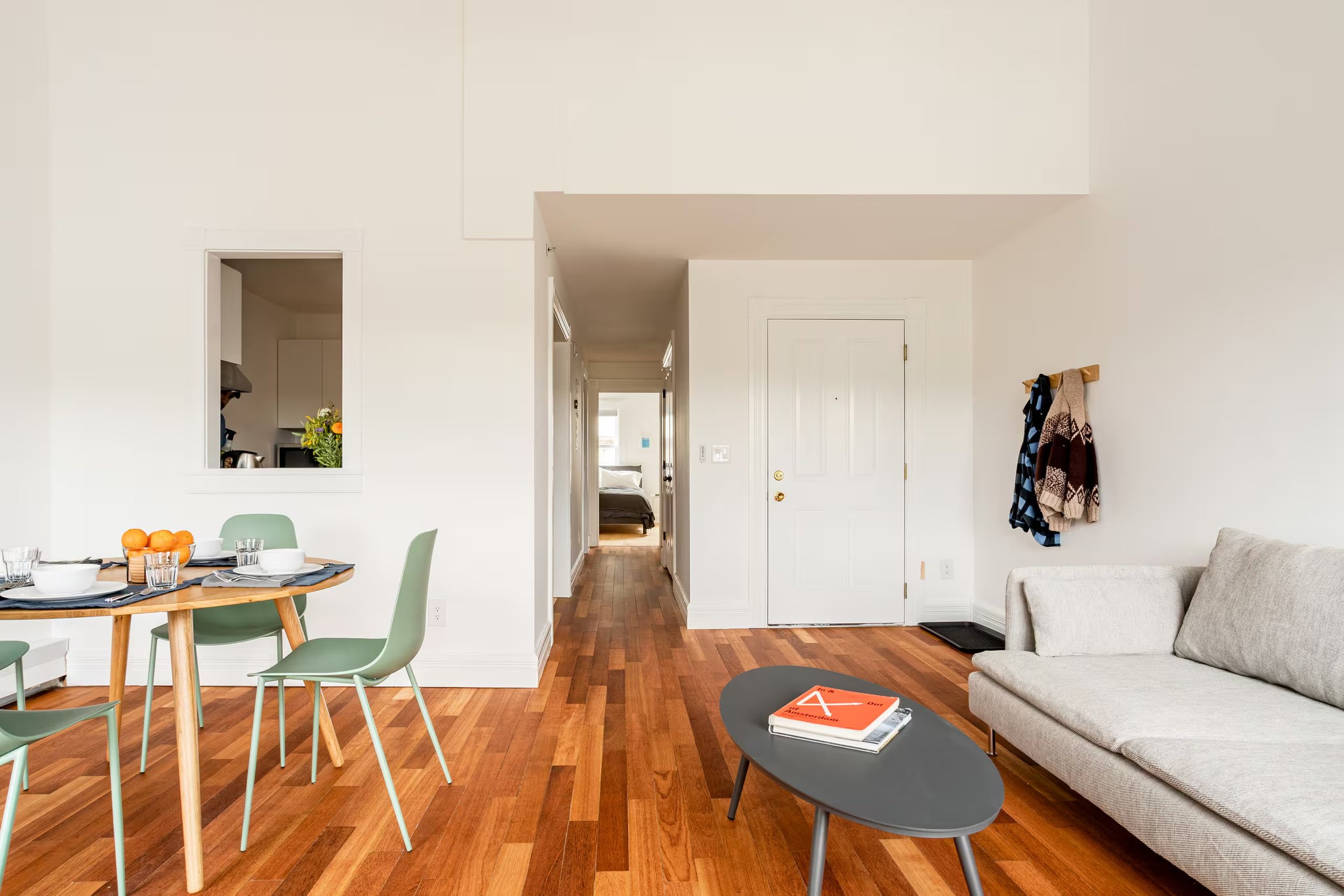 Sunlit living and dining area at Above SpringRise, a Catskill Village vacation apartment for two guests, featuring hardwood floors, modern furnishings and an open layout.