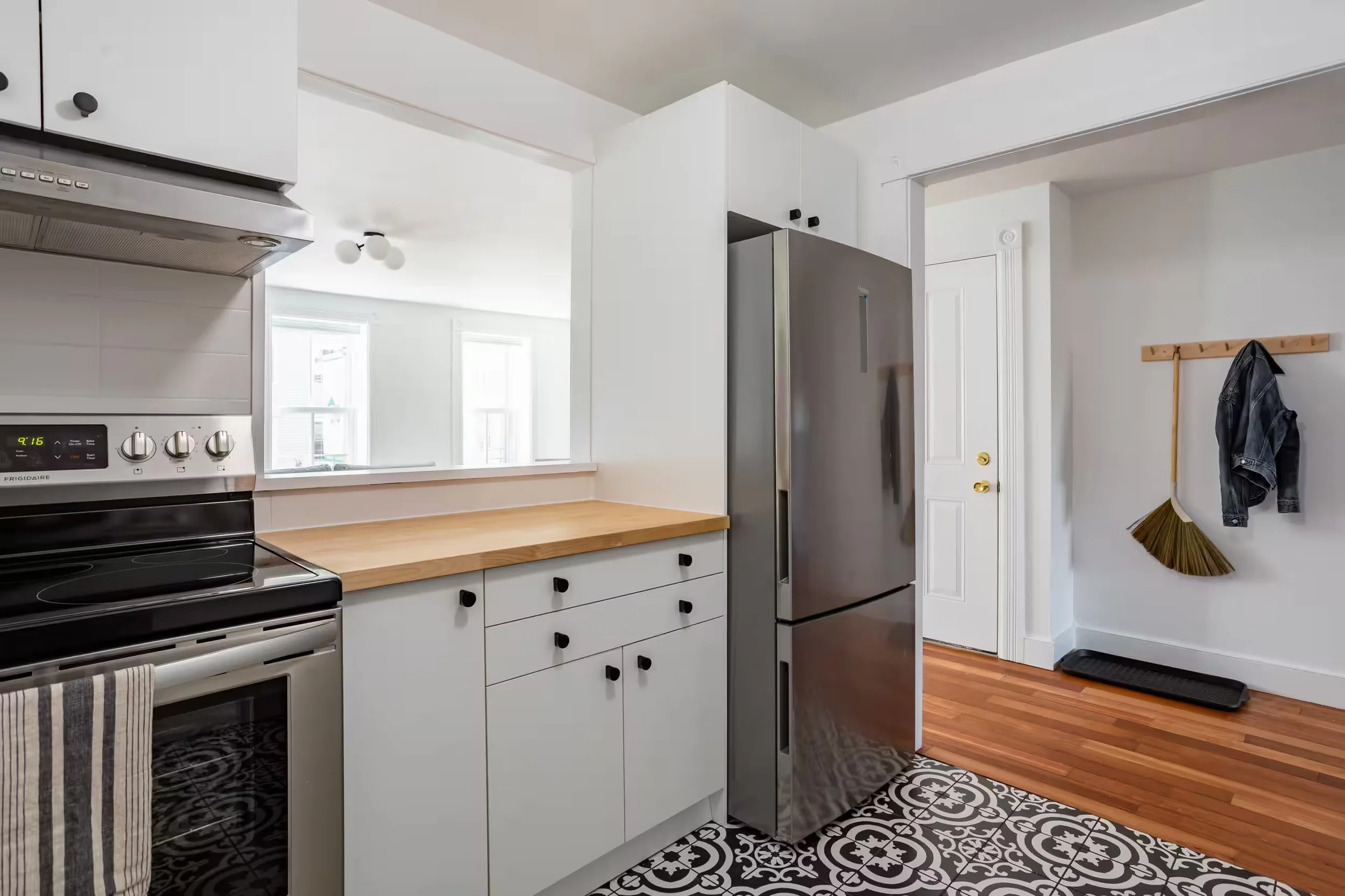 Fully equipped kitchen at Within Reach vacation apartment in Catskill Village, New York, featuring stainless steel appliances, white cabinets, wood countertops, and hardwood floors.