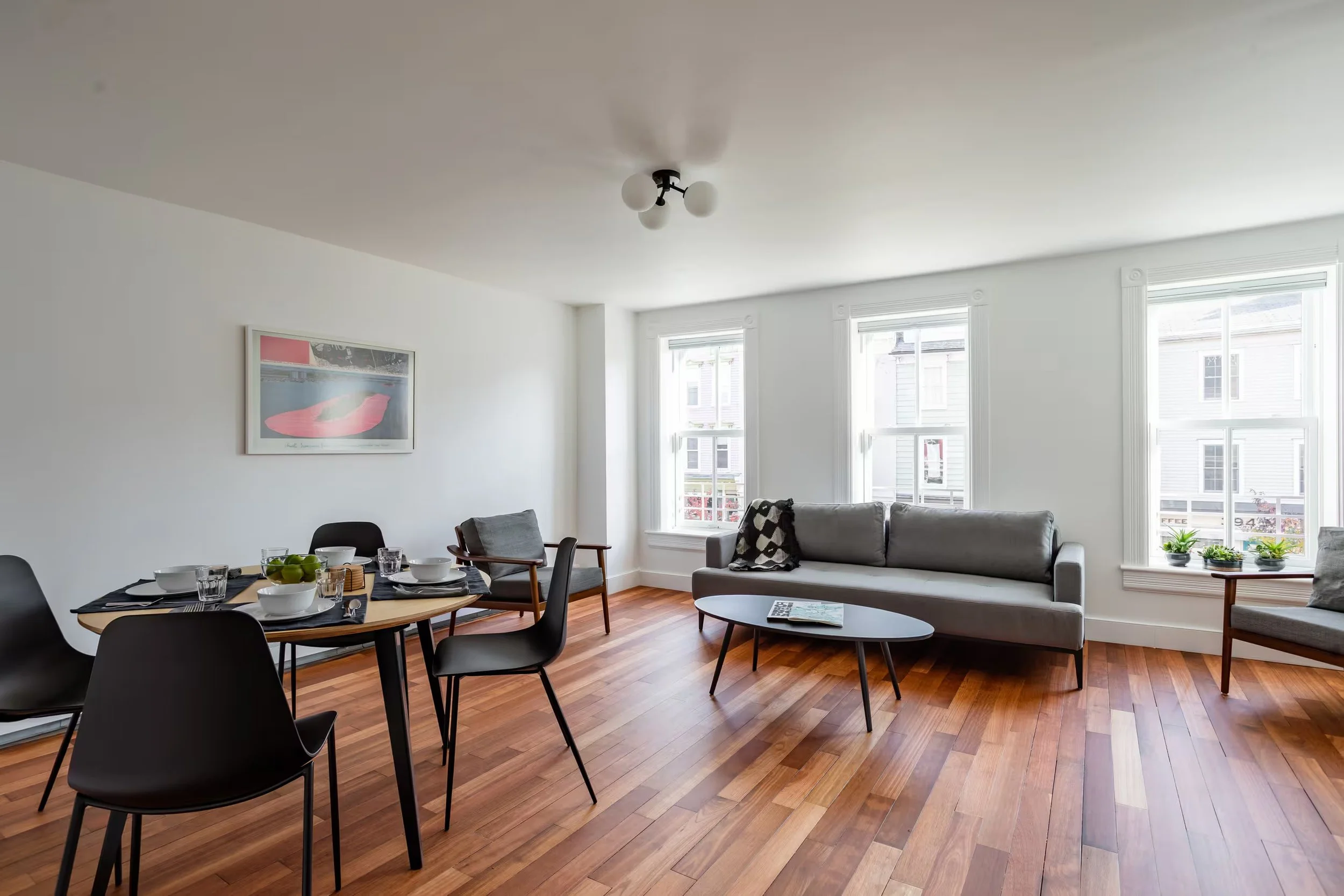 Bright living and dining room at Within Reach, a Catskill Village vacation apartment for up to four guests, featuring hardwood floors, comfortable seating and large windows.