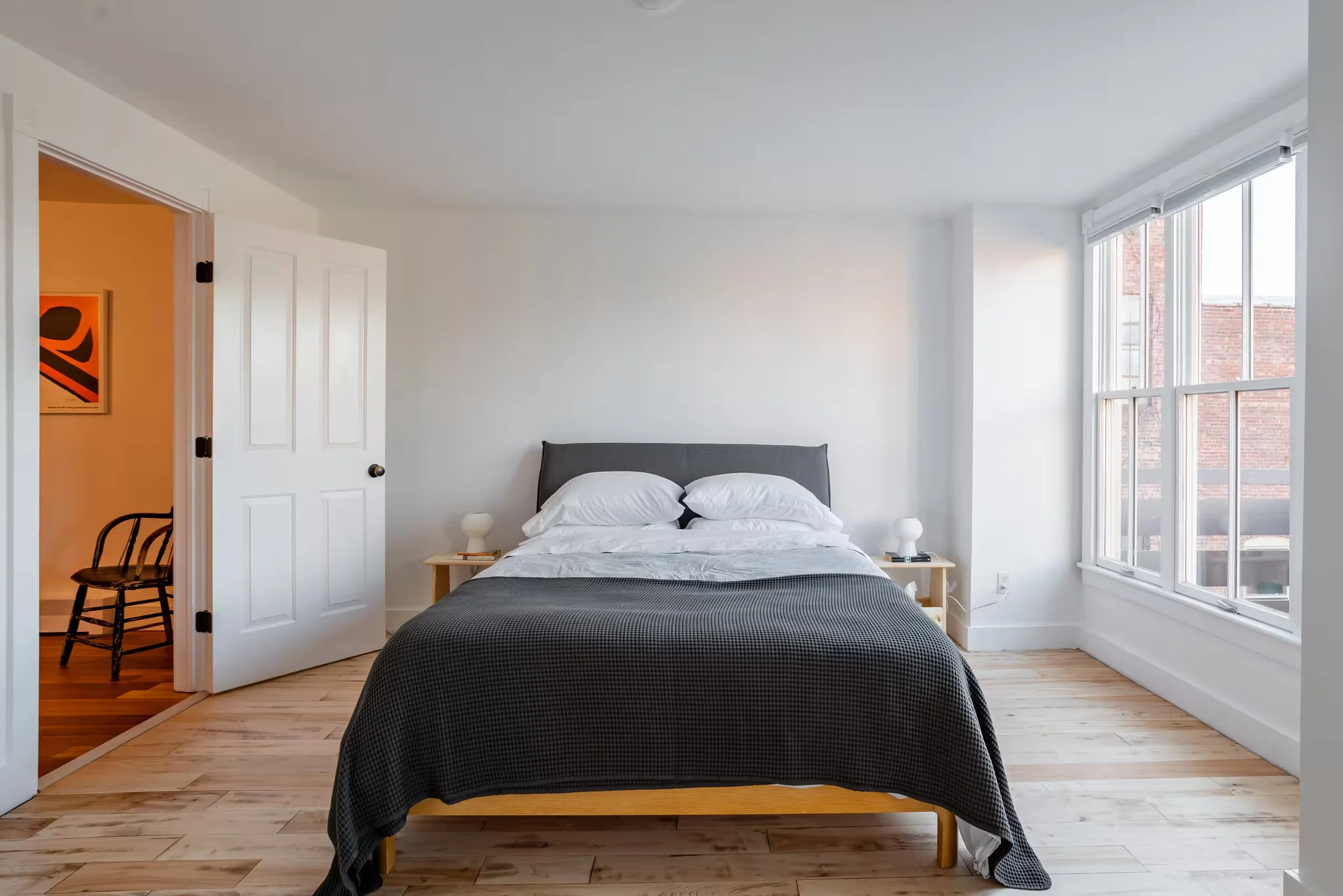 Bright bedroom at Within Reach vacation apartment in Catskill Village, New York, featuring a queen-size bed, hardwood floors, and large windows.