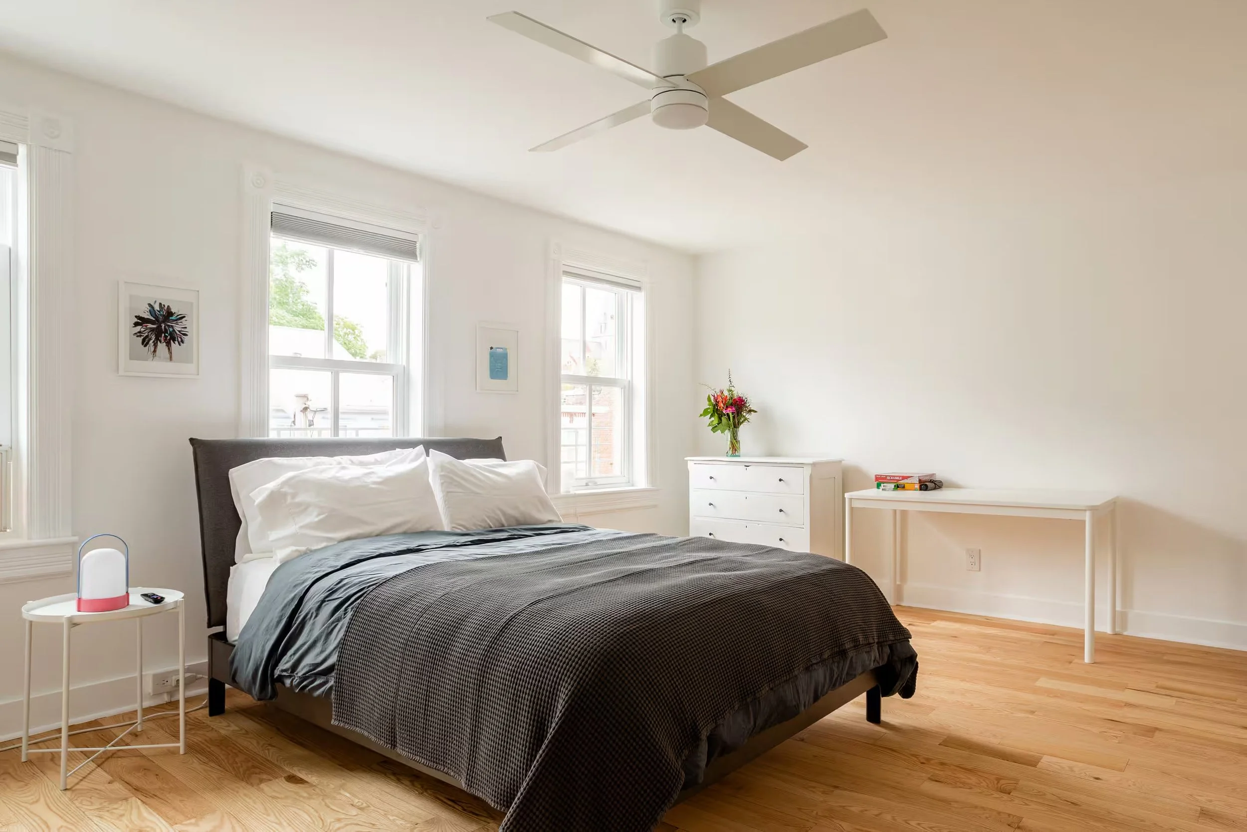 Bright bedroom at Above SpringRise vacation apartment in Catskill Village, New York, featuring a comfortable bed, hardwood floors, ceiling fan, and large windows.