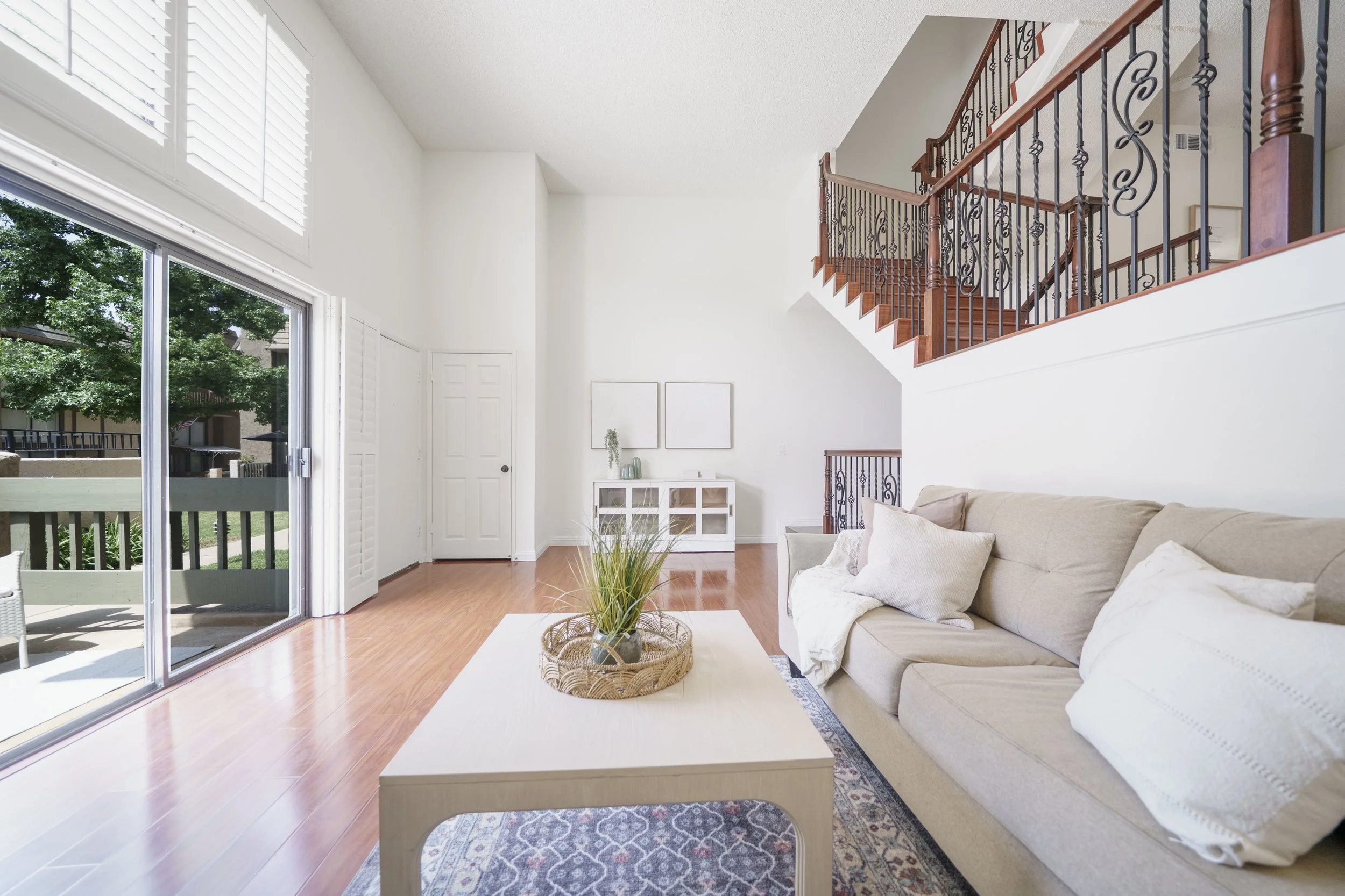 Bright living room with soaring ceilings, a balcony and garden-facing windows