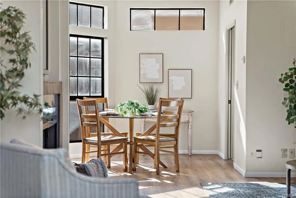 Sunlit dining area with tall windows, wood furniture and warm natural finishes