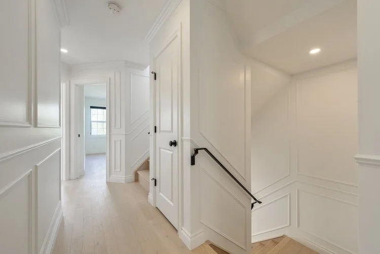 Interior hallway and staircase in a bright, modern home with white walls and trim.