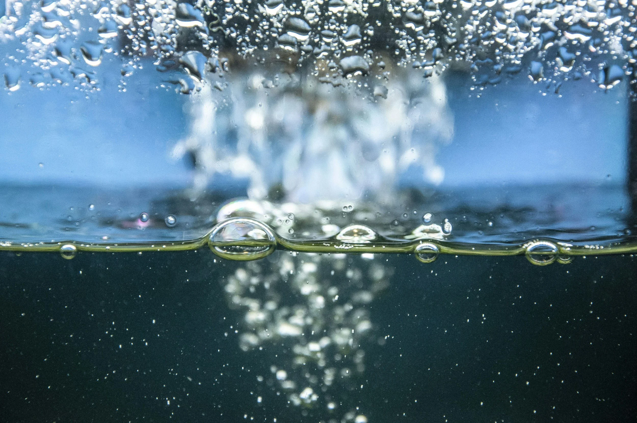 Close-up of water with bubbles and droplets forming as a splash occurs, captured underwater or in a splash zone.