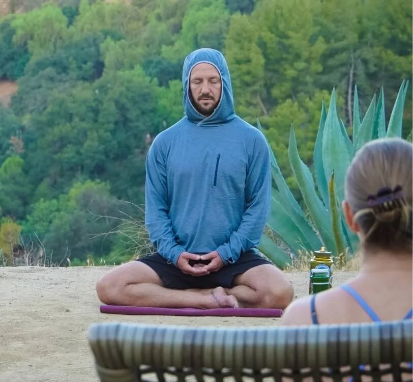 Man seated cross-legged outdoors with eyes closed