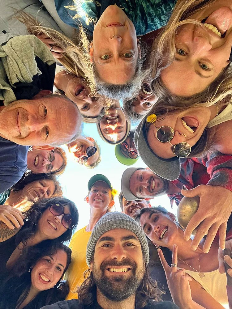 Breath School participants in a circle looking down at the camera, smiling and having fun.