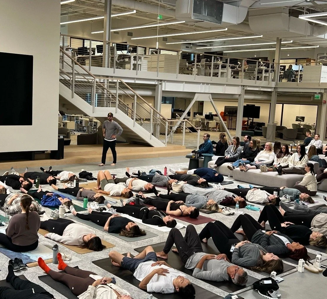 Employees lying on mats in an open office atrium during a breathwork session
