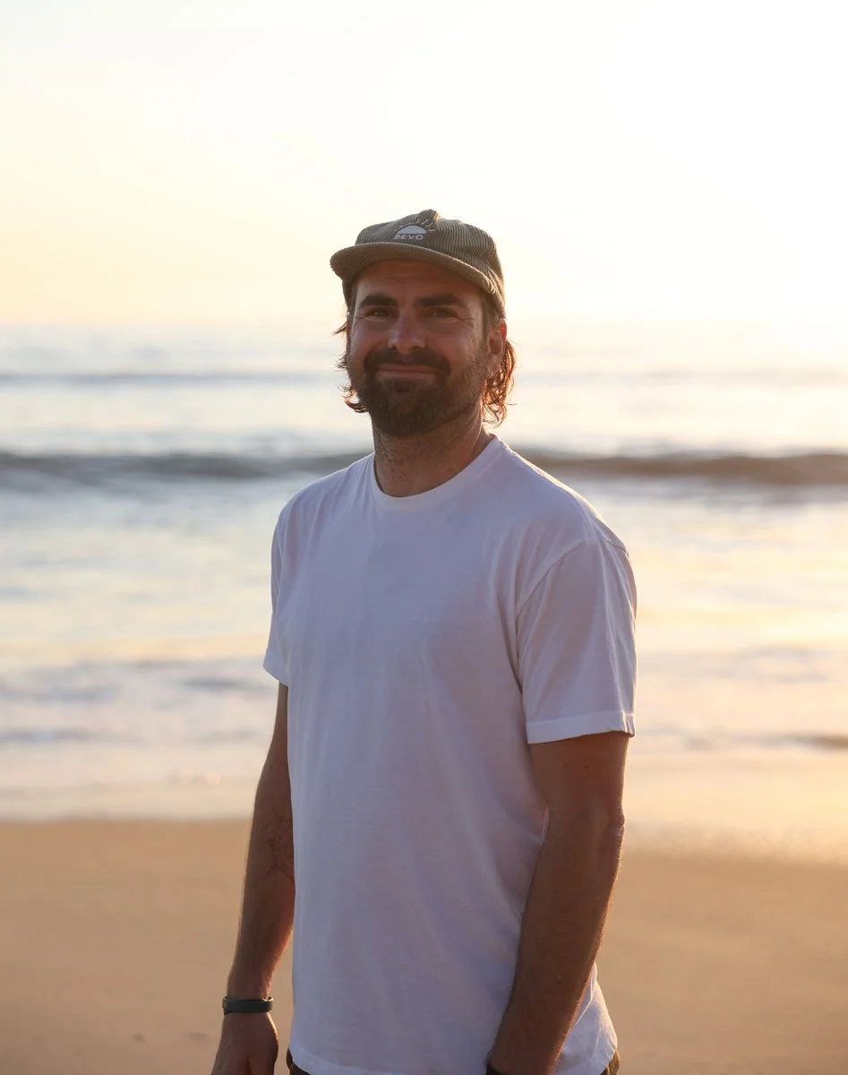 Reis Paluso standing on a beach at sunset with the ocean in the background.