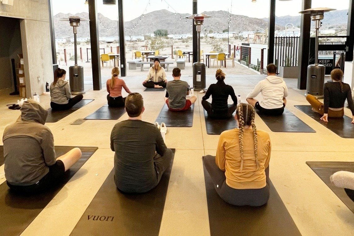 Team seated on mats on a deck overlooking hills