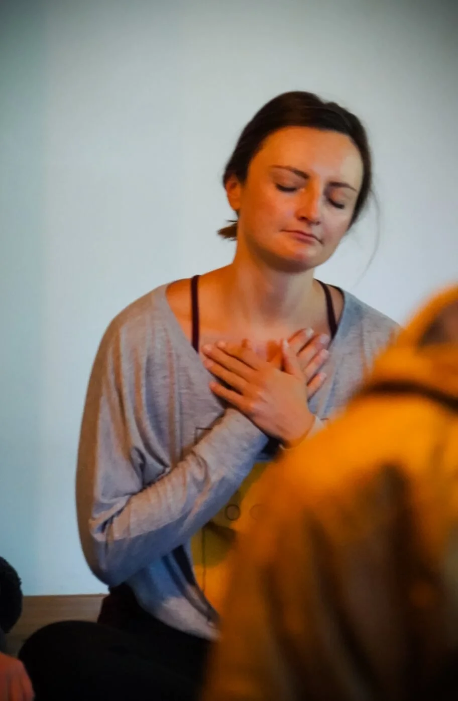 Woman with eyes closed and both hands on her chest