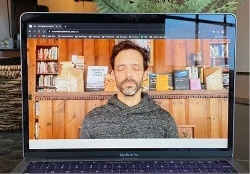 Laptop screen showing a man guiding a live breathwork session
