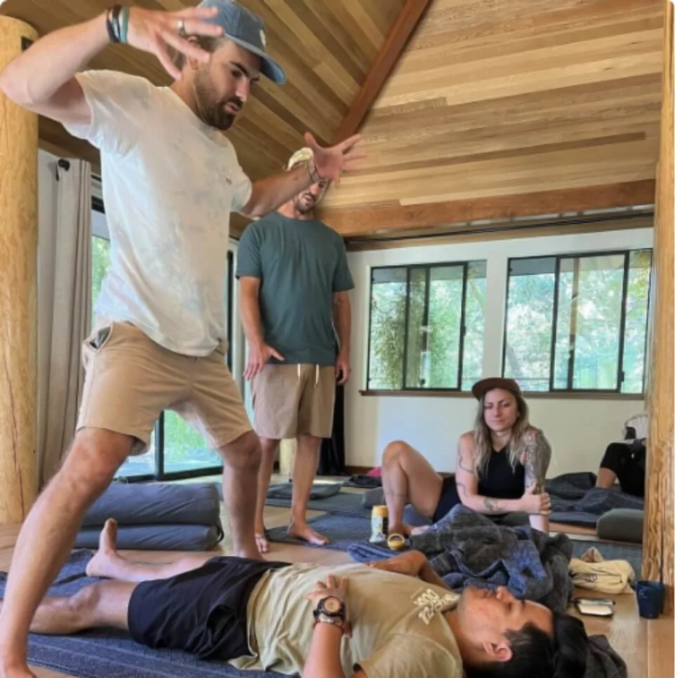 Instructor demonstrating a breathing position over students on mats