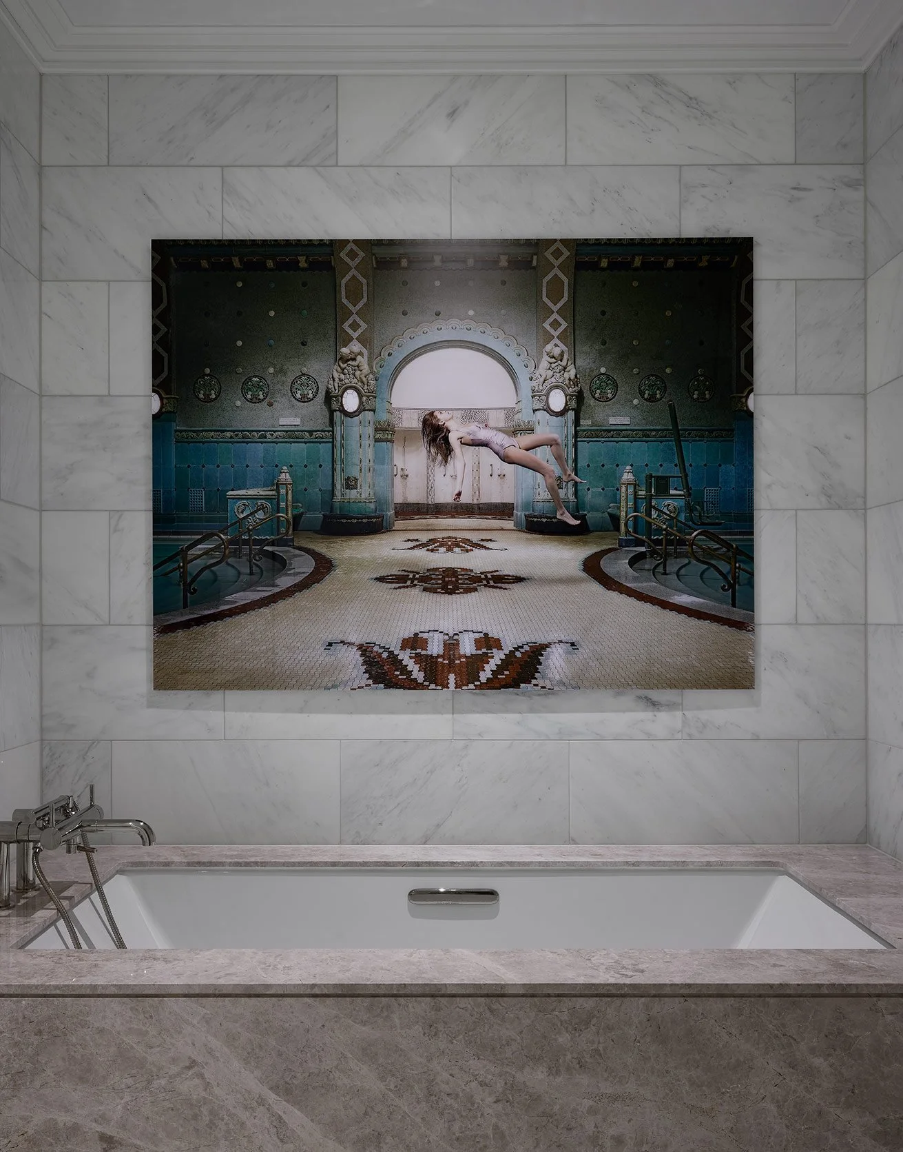 A bathroom with a large mirror showing an artwork of a woman in a swimsuit floating above a decorated pool area.