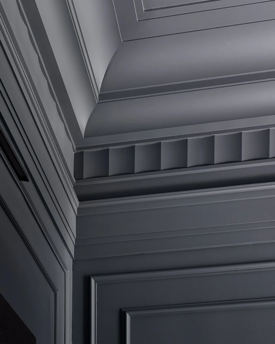 Close-up view of a gray, decorative ceiling featuring layered molding and geometric patterns.