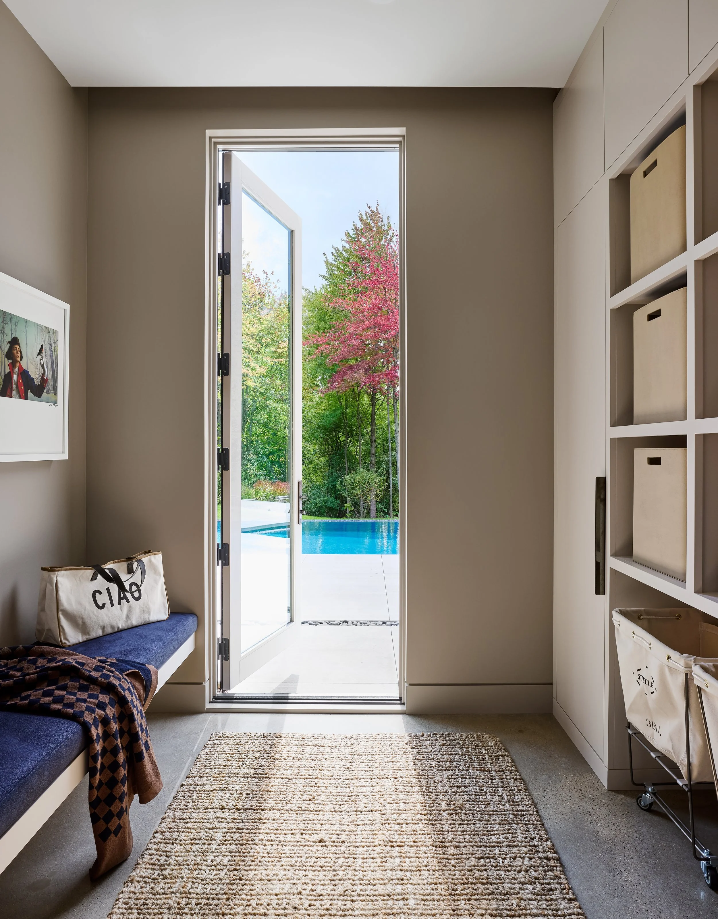 A view from inside a room looking out through a glass door to a backyard with a pool and colorful trees.