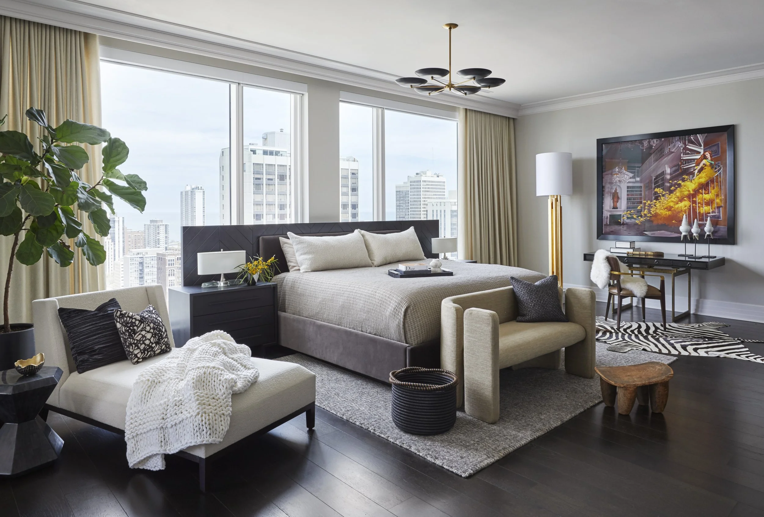 Modern city-view living room with large windows, beige bed, white chairs, black side tables, a large flat-screen TV, and decorative elements including plants, cushions, and a zebra-patterned rug.