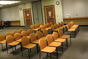 Empty chairs arranged in rows in a conference room or waiting area.