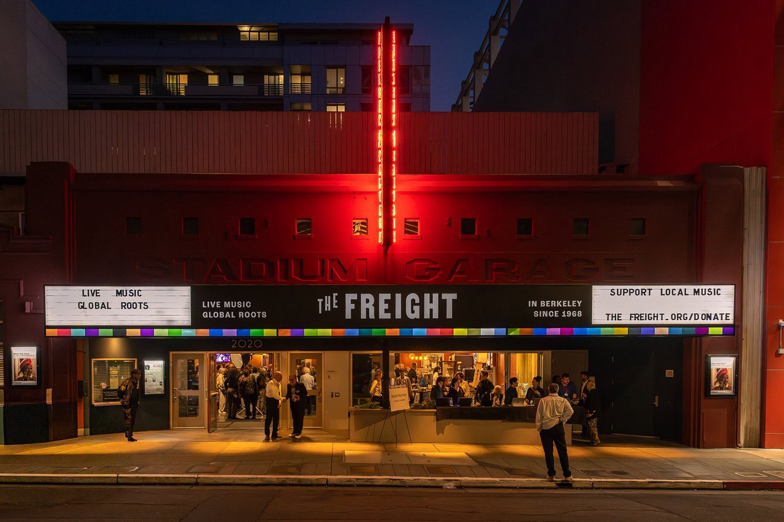Night view of the facade of the Stading Garage, hosting an event called The Freight, featuring live music and supporting local music in Berkeley since 1968, with people entering and leaving the venue.