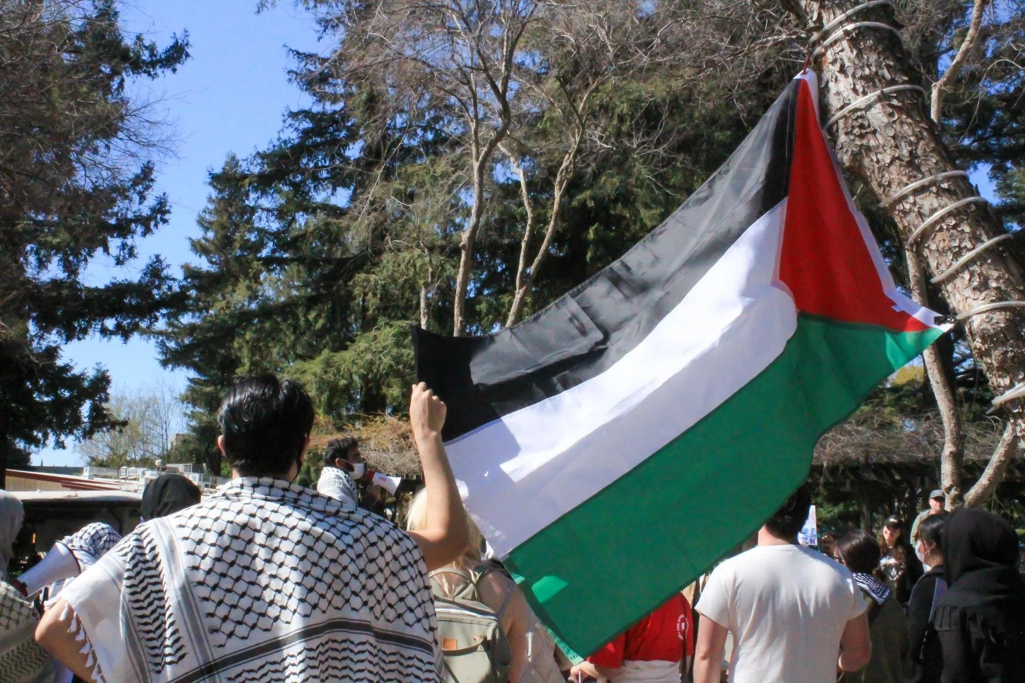  A protester holds the Palestinian flag up while they chant “Free Palestine,” Tuesday, March 11, 2025. The students said they felt liberated after speaking their minds about the conflict. (photo by Jada Portillo) 