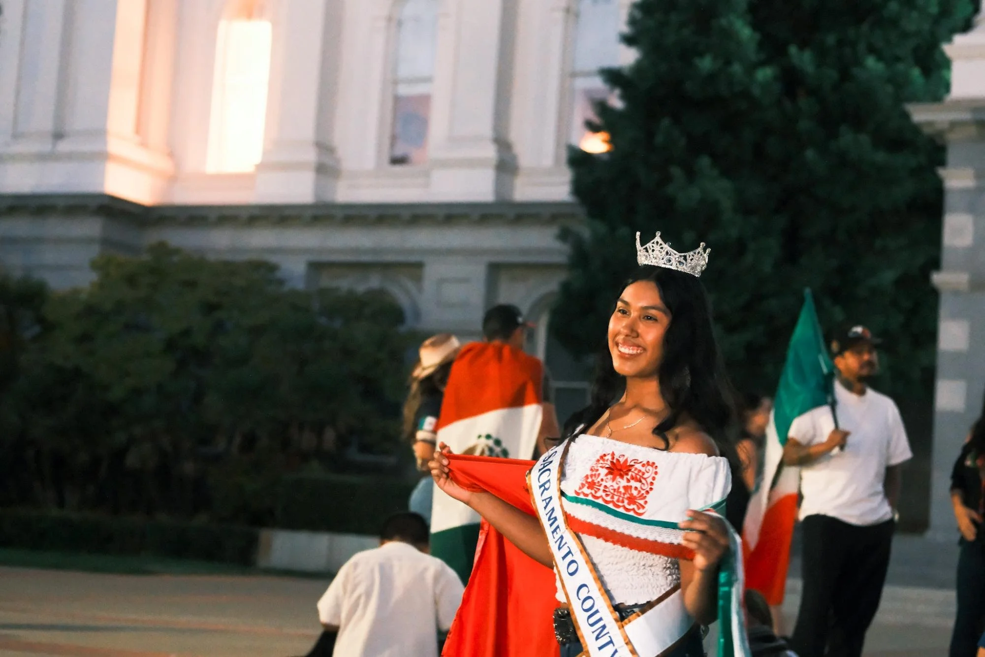  Una mujer joven sostiene la bandera Mexicana detrás de ella durante el evento Lunes, Sept. 15, 2025. Banderas Mexicanas se miraban por todos lados durante el evento. (photo by    Ruth Finch   ) 