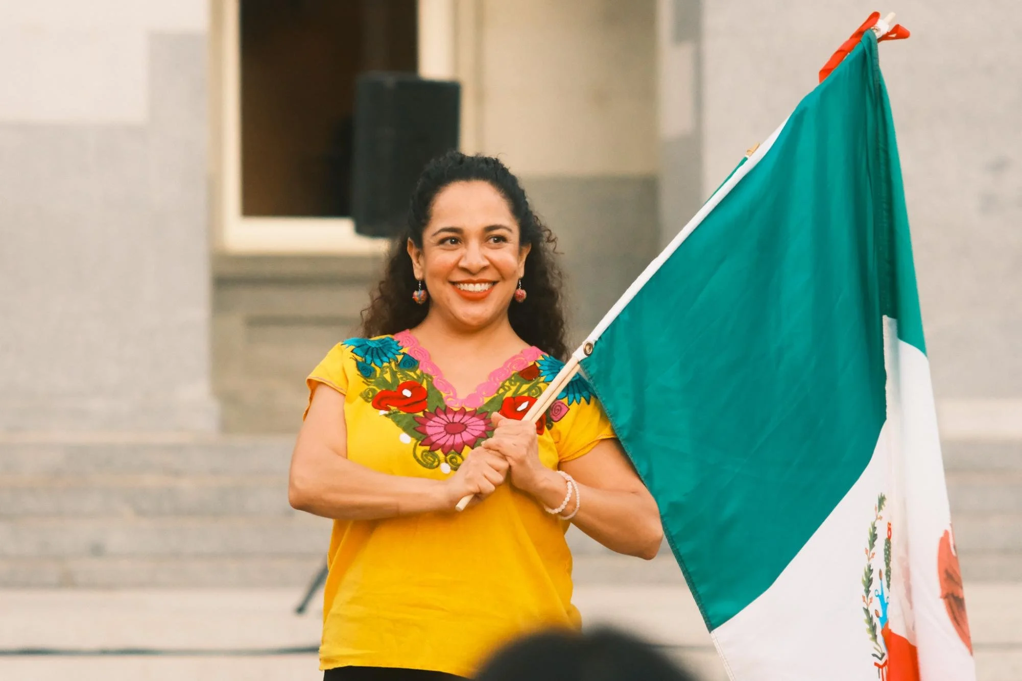  Mujer sonríe mientras sostiene su bandera Mexicana Lunes, Sept. 15, 2025. Tiene puesta una huipil, que es una ropa tradicional usada por las mujeres indígenas de Central México y América Central. (photo by    Ruth Finch   ) 