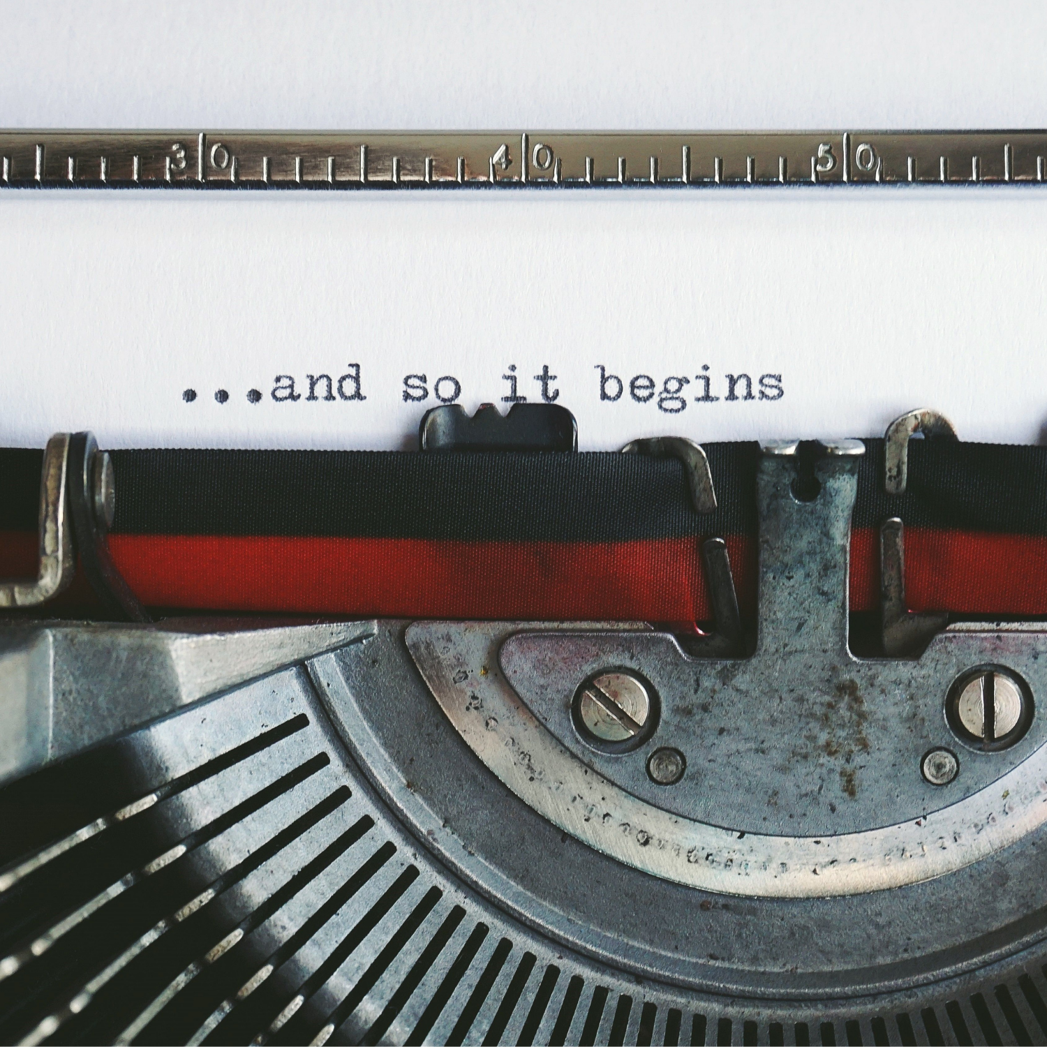 Photo of a retro typewriter and paper, with typed words which read "...and so it begins".