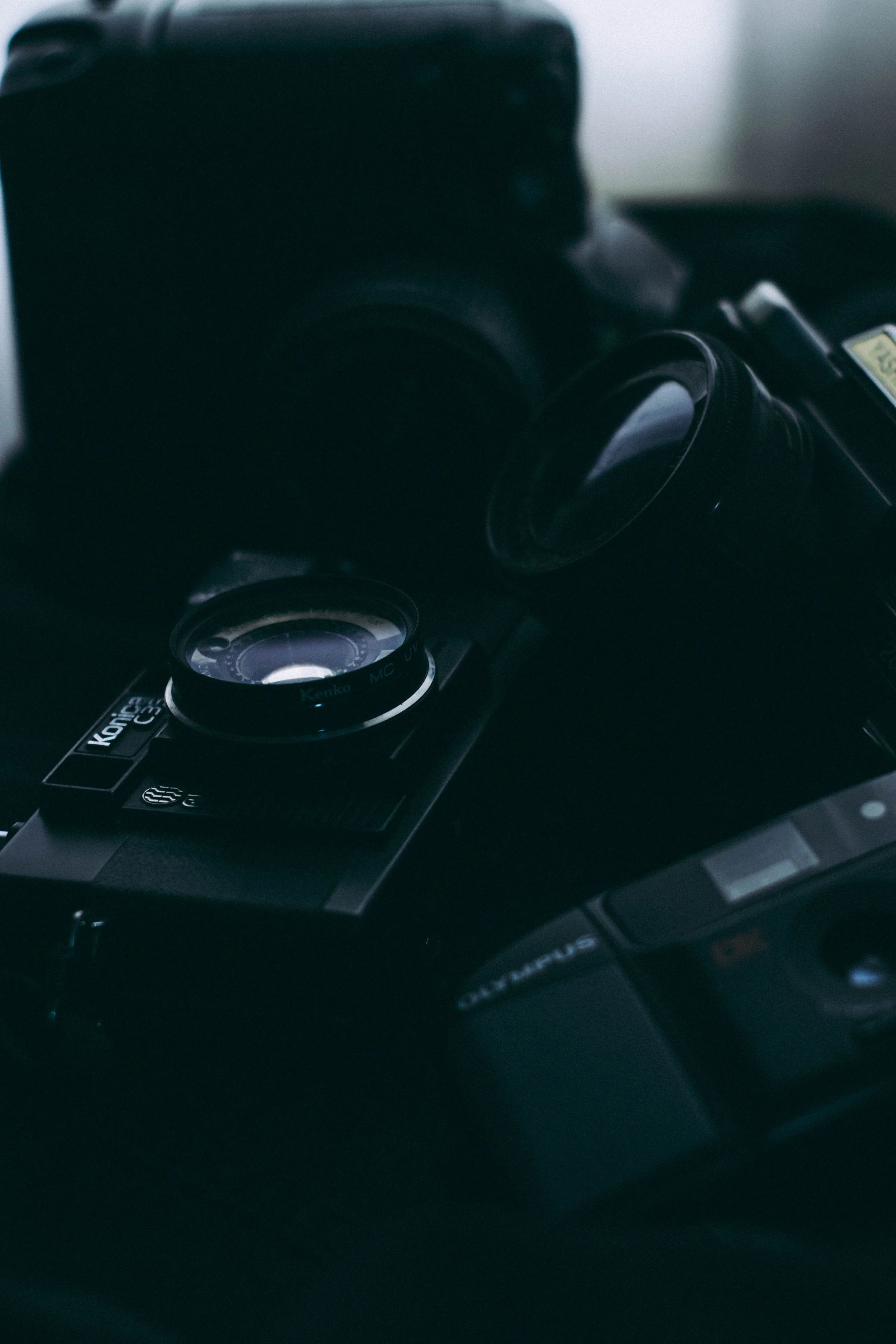 Close-up of a black camera with a zoom lens, placed on a dark surface with a blurred background.