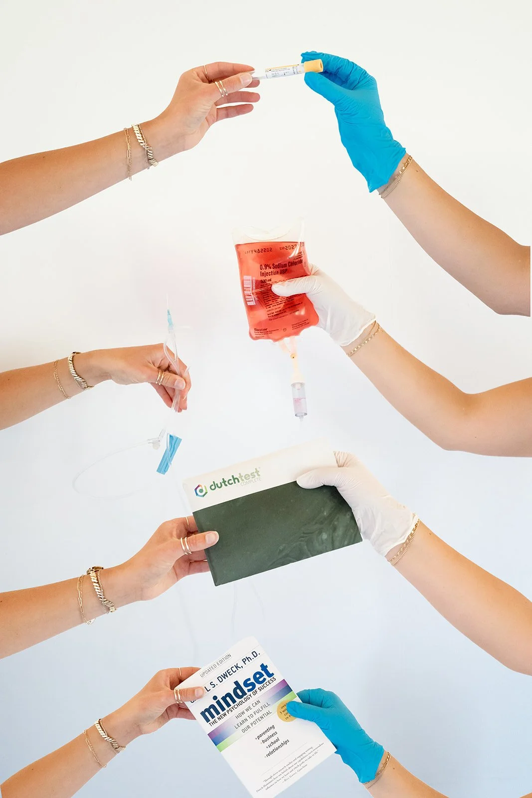 Medical professionals preparing a blood sample, holding a test tube, syringe, brochure, and a packet labeled 'mindset' with gloves on.