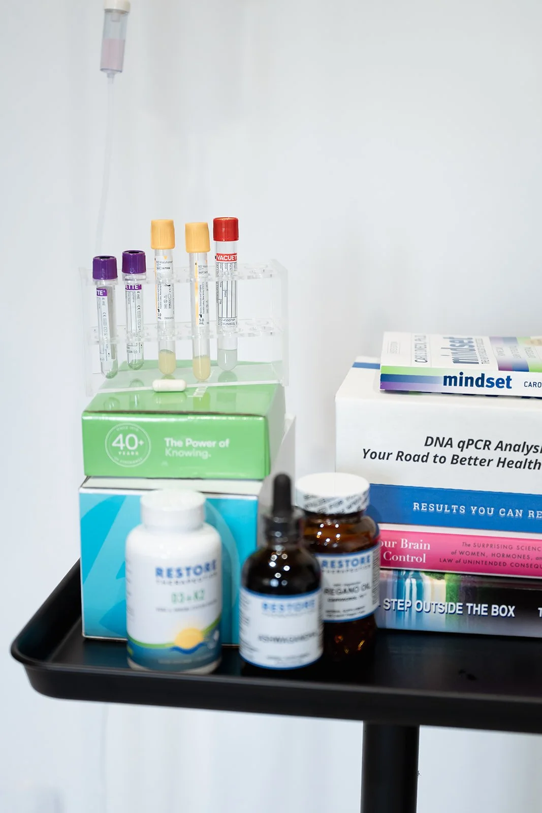 Medical supplies including test tubes, bottles, and informational books on health and DNA analysis on a black tray
