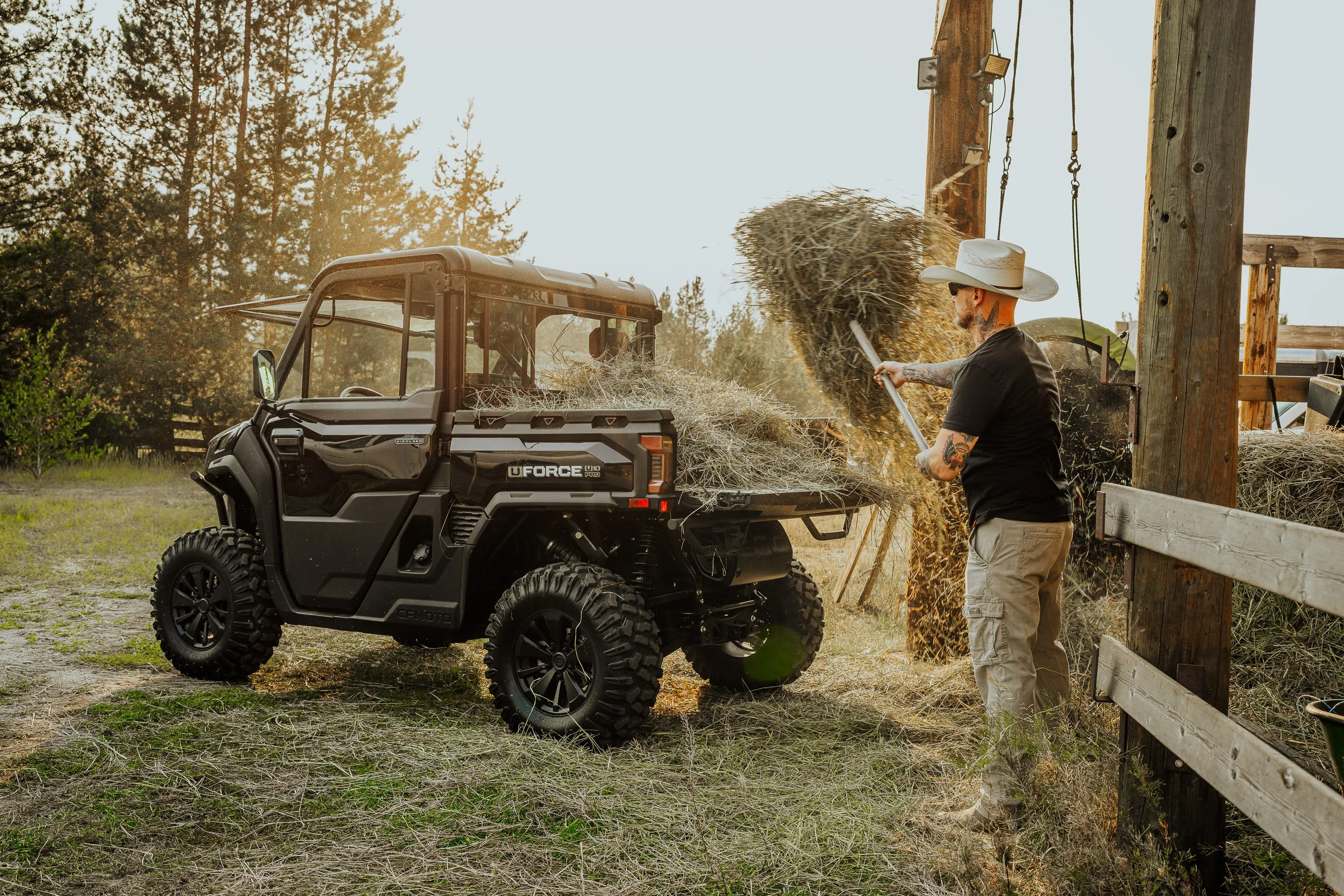 Farmer forking hay beside a CFMOTO UFORCE side-by-side
